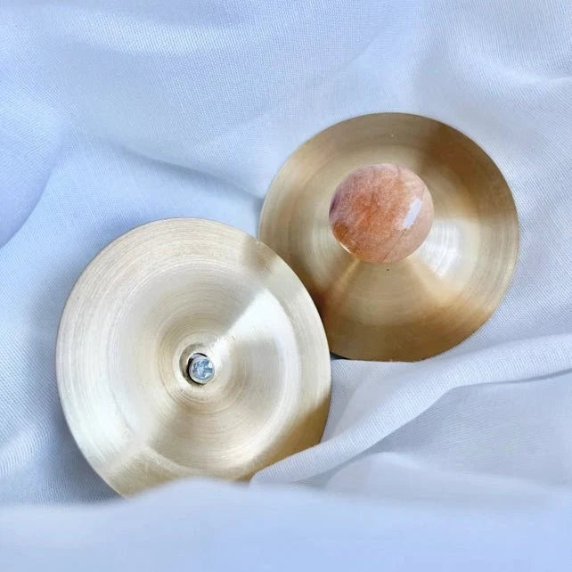 Two copper cymbals on a light fabric background