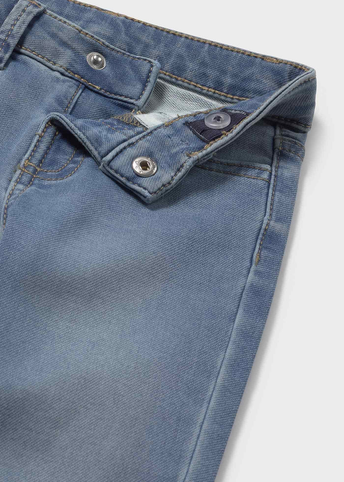 Closeup of button, simulated fly and inner elastic on Mayoral baby jeans; soft light-wash denim texture.