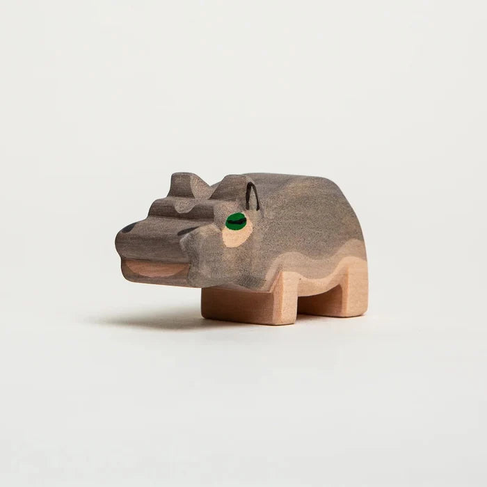 Wooden hippo figurine on a light gray background