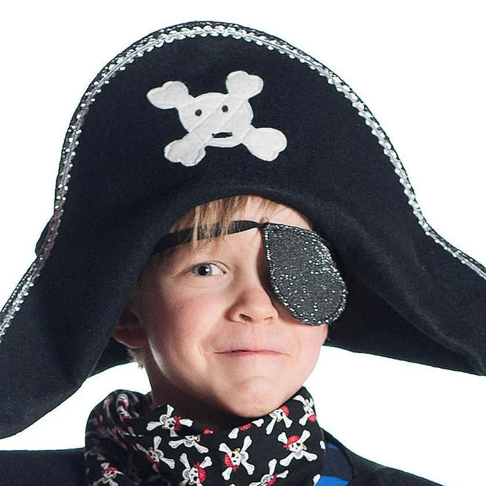 Child wearing a black pirate hat with white skull and crossbones, eyepatch and scarf on a white background