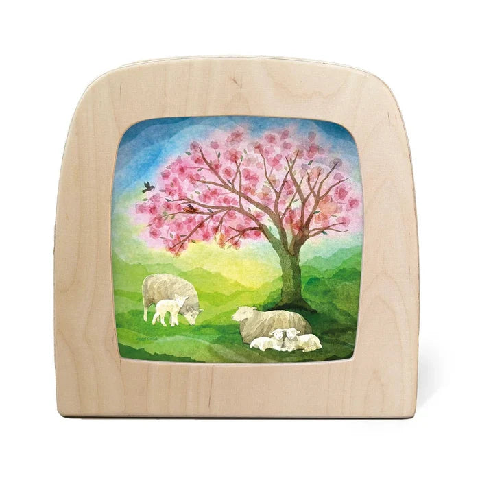 Silhouette of sheep laying under a tree with pink blossoms