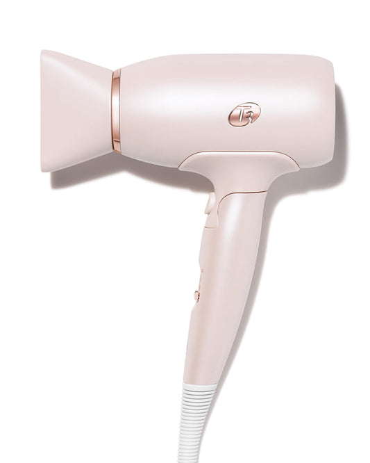 Pink hair dryer with rose gold accents on a white background