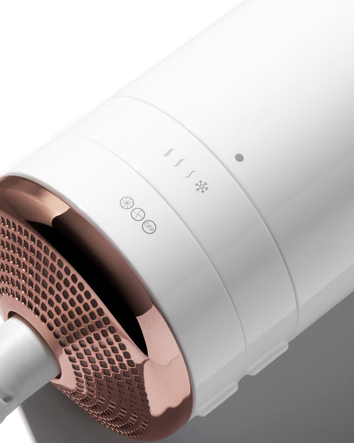 Close-up of a white hair dryer with rose gold accents on a gray background