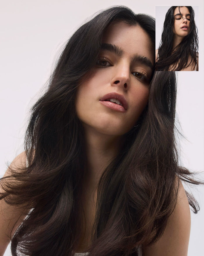 Woman with long dark hair against a plain background