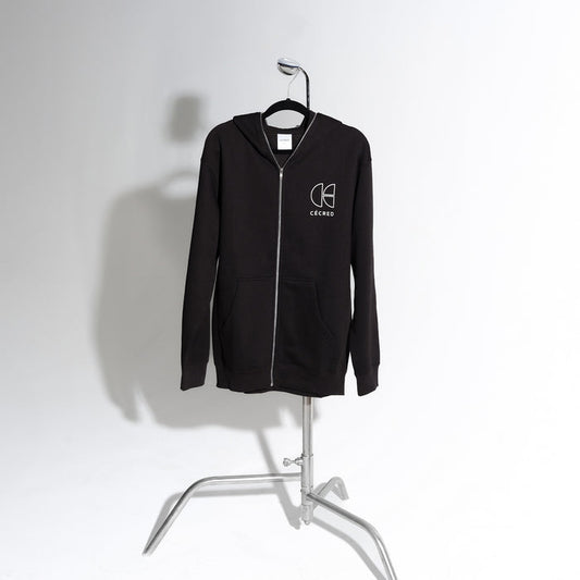 Cécred black zip-up hoodie displayed on a standing chrome garment rack against a soft white background, showcasing the full silhouette and front zip detail