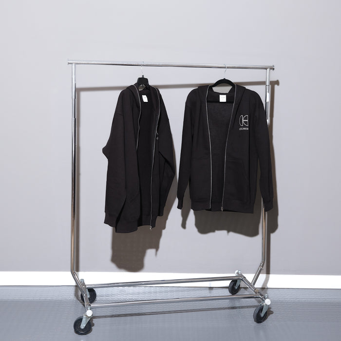 Two Cécred black zip-up hoodies hanging on a rolling coat rack, one facing forward showing the front logo and one turned to show the side profile
