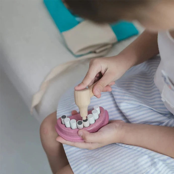 Child playing with a dental model toy on a white surface.