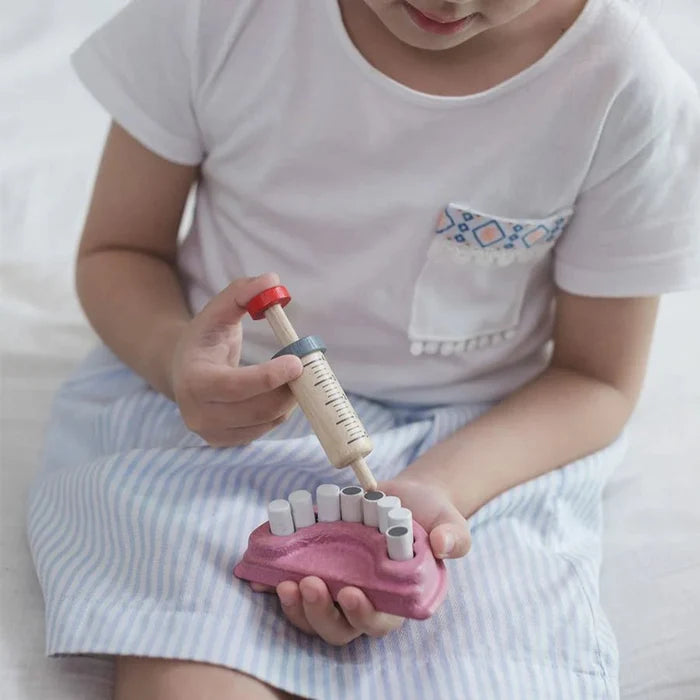 Child playing with a toy dental set on a white background