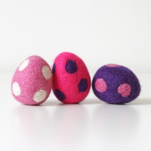 Three felted eggs with polka dot patterns on a white background
