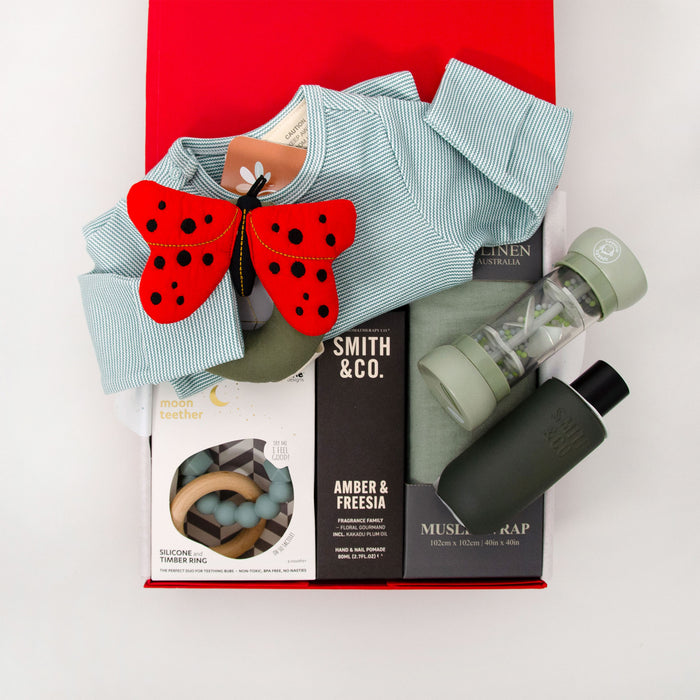 Collection of baby products including a long sleeve romper, ladybird-shaped rattle, teether, muslin wrap hand cream and room spray. $195.00