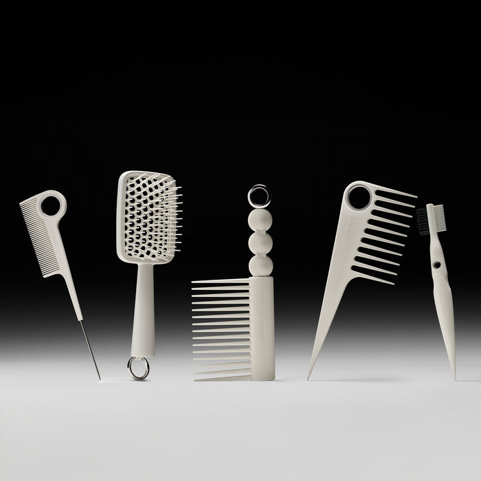 Set of hair styling tools including combs and a brush on a gradient background