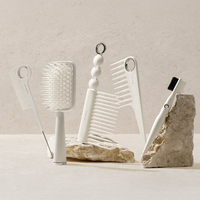 Set of white hair care tools on a stone surface with a neutral background