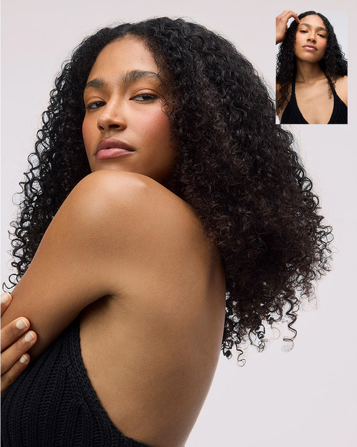 Woman with voluminous curly hair against a plain background