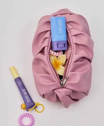 A pink bag is full of Frizz Control Stick and  Frizz Finishing Wand with hair bands and other hair accessories