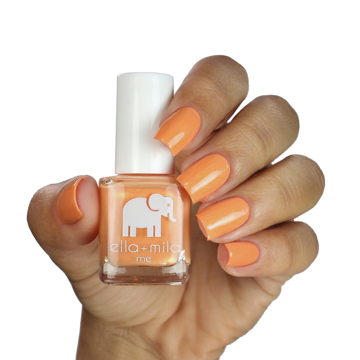 Mango Pop orange nail polish on a medium-deep skin tone, hand holding the bottle