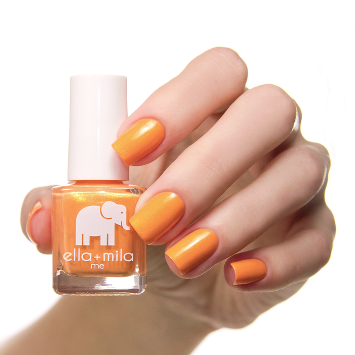 Mango Pop orange shimmer nail polish swatch on a light skin tone with the bottle