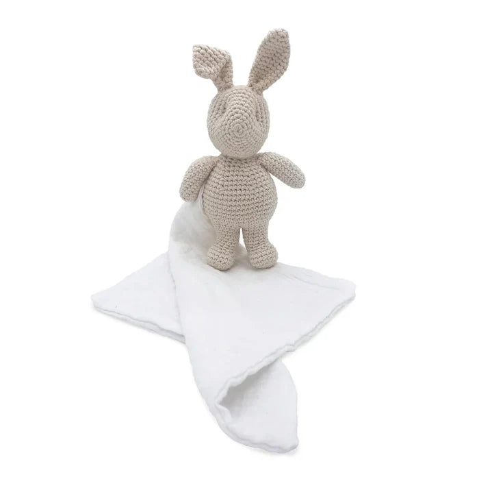 Crocheted rabbit toy with a white blanket on a white background