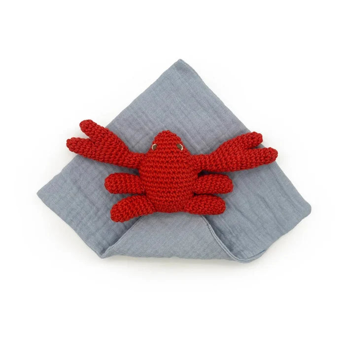 Red crocheted crab toy on a gray fabric background