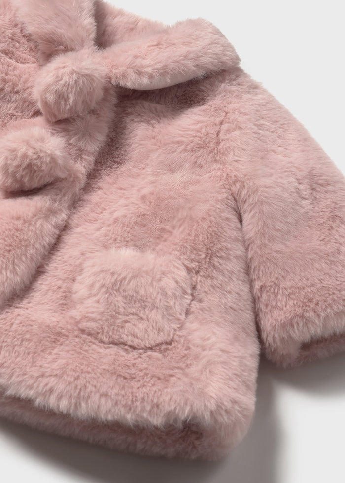 Close-up pompom detail and pockets on newborn faux fur jacket