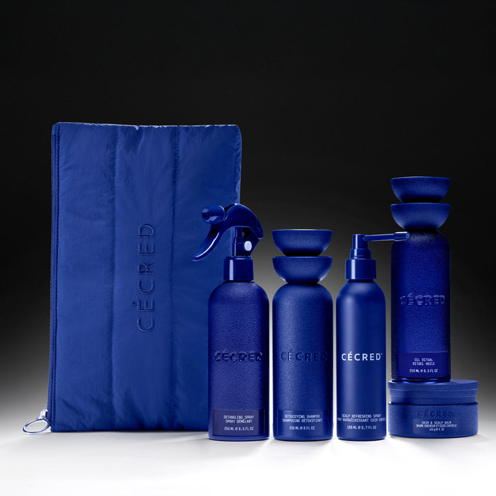Blue skincare collection set including spray bottle, two cylindrical containers, pump bottle, stacked bowls, and jar with dra