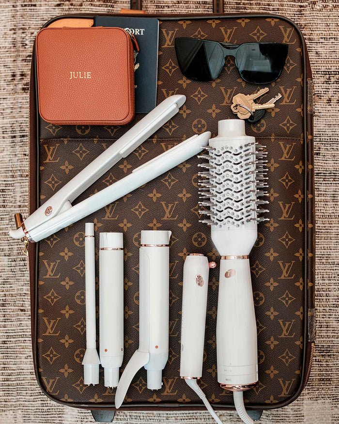 White hair styling tools on a patterned surface with a brown case.