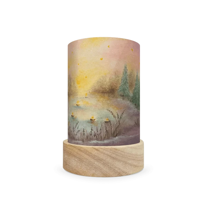 Decorative lamp with a wooden base and painted scene  of christmas trees on the edge of a lake on a white background