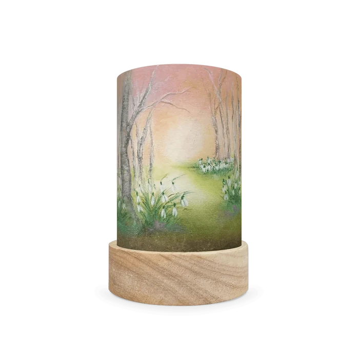 Decorative cylindrical lamp with wintery white flowers and leafless trees on a white background